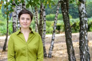 Henriette Heise (dunkelbraunes, kurzes Haar, Lächeln) vor dem Hintergrund junger Birken